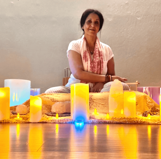 Woman sitting on floor behind many lit candles